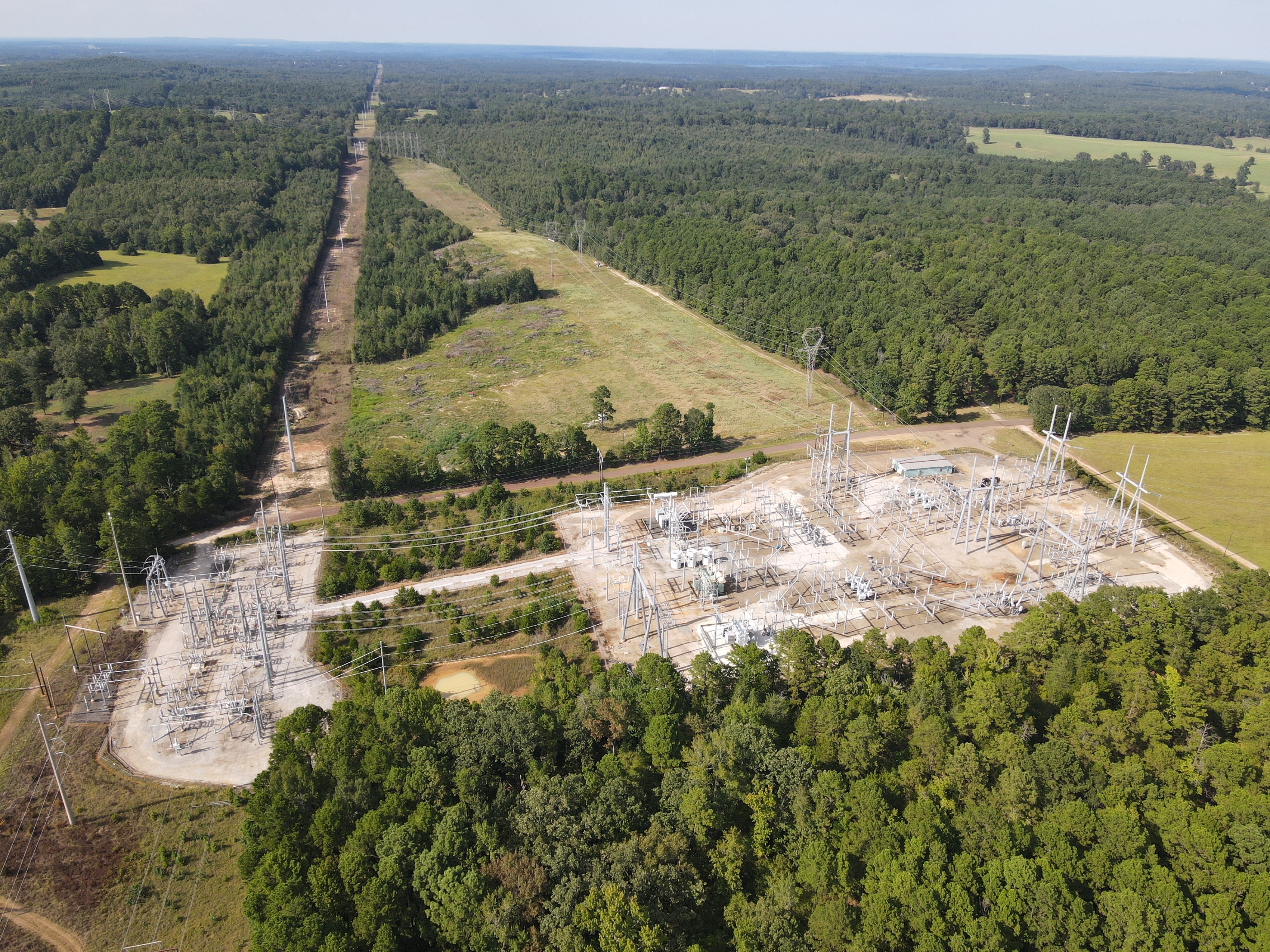 Transmission corridor running to the horizon beside an energized substation